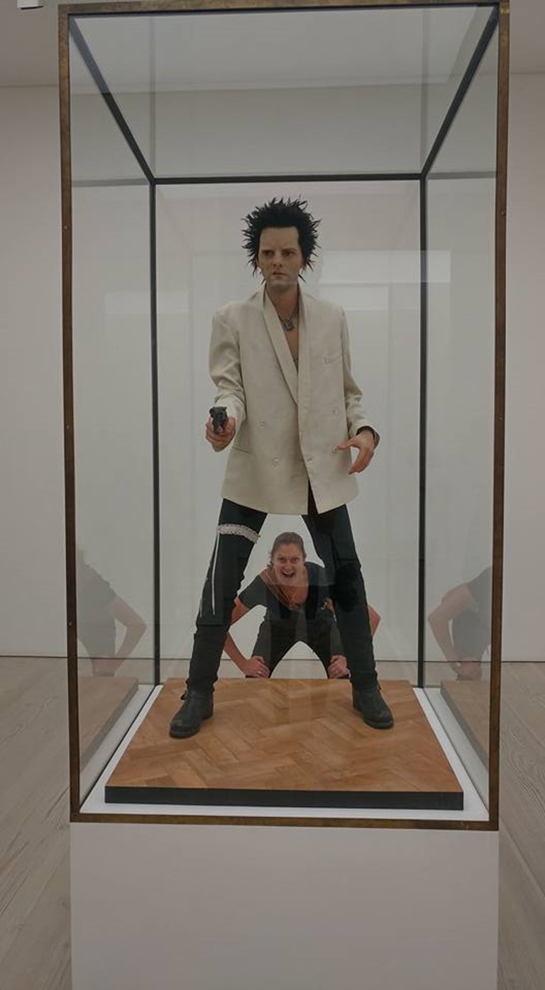 life size statue of man in white tuxedo, with a gun and a suspender belt.